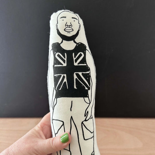 Hand holding screen printed doll of Stormzy wearing Union Jack vest and combat trousers