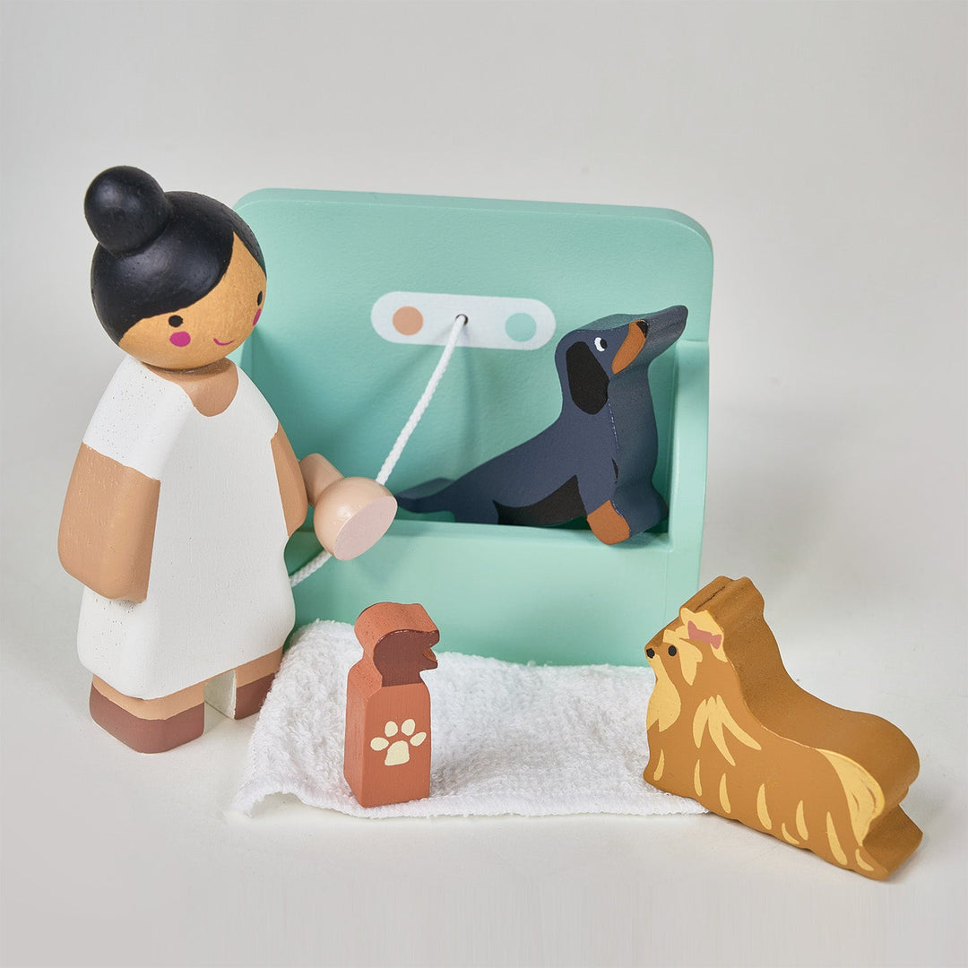 Wooden toy figure of a person with a dog and a leash on a light gray background