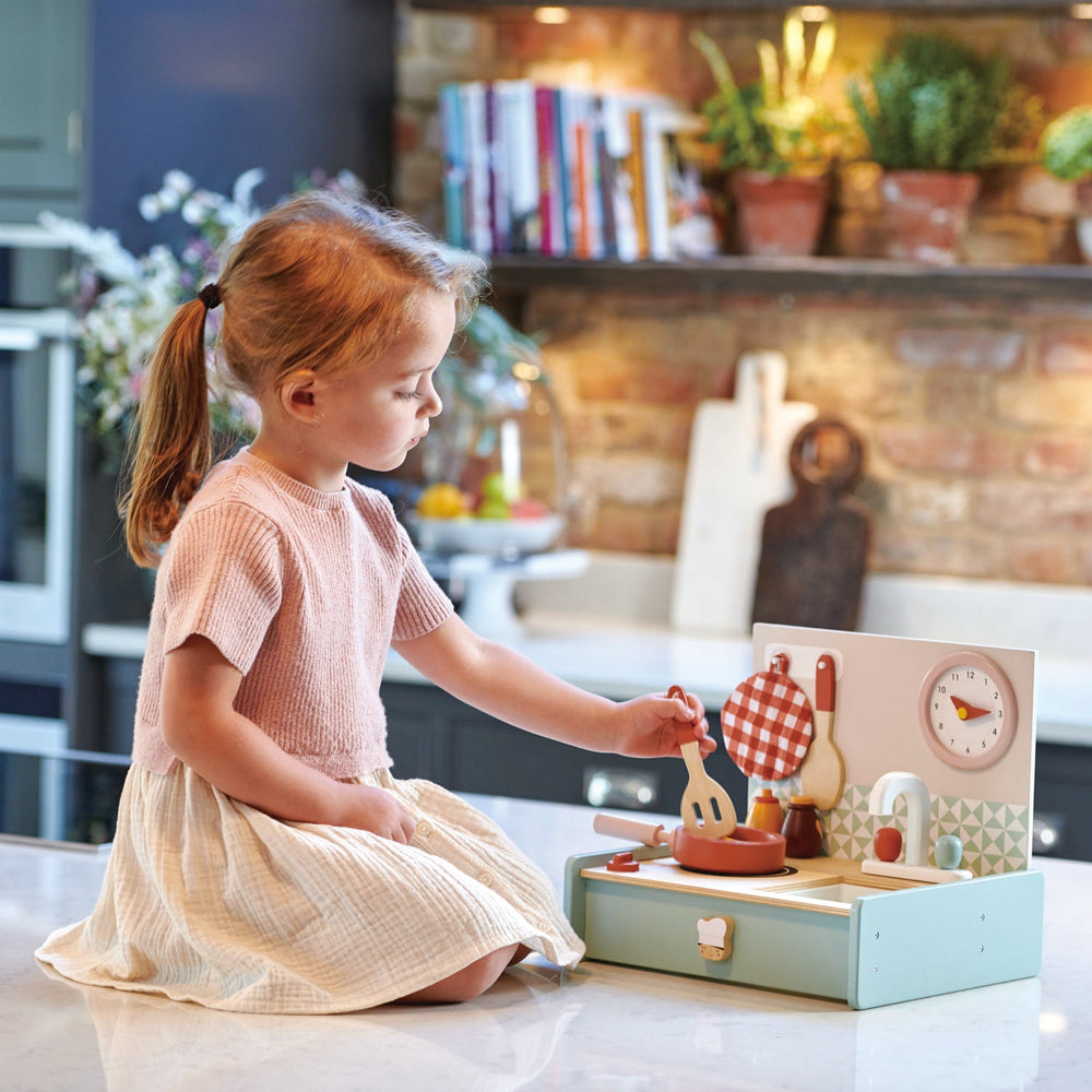 Child playing with a wooden kitchen set in a kitchen setting
