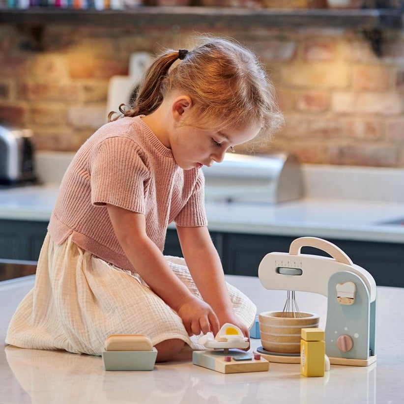 Child playing with toy mixer set on a countertop