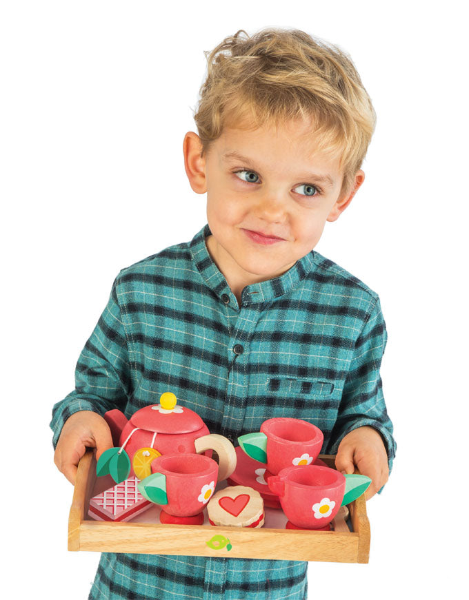 Child holding a toy tea set on a white background