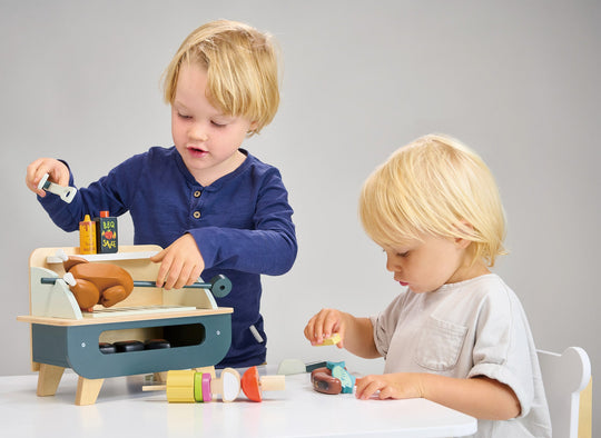 Two children playing with a wooden toy set on a grey background