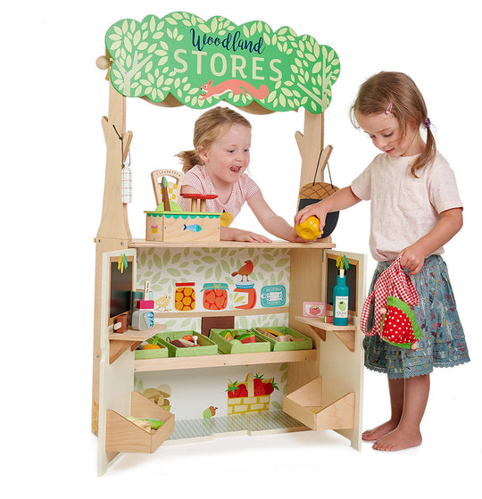 Children playing with a wooden toy store set on a white background