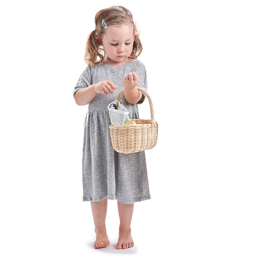 Young girl in a grey dress holding a wicker basket on a white background