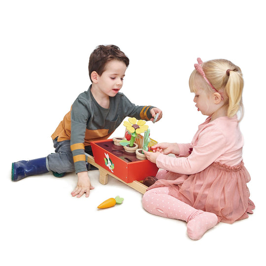Two children playing with a toy garden set on a white background