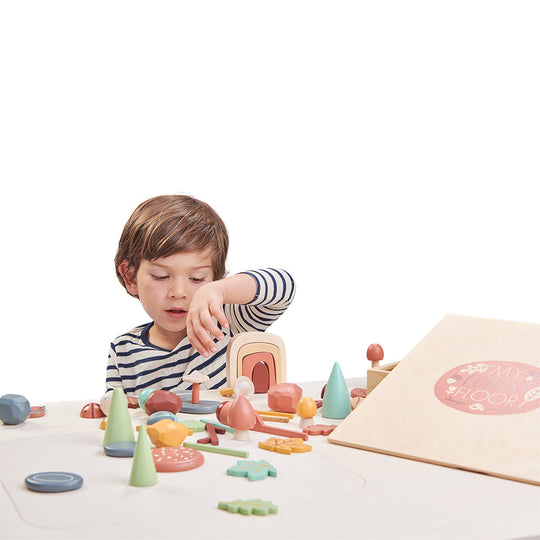 Child playing with wooden toys on a white surface