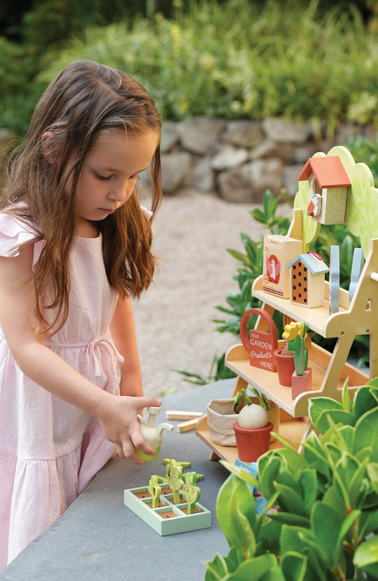 Young girl playing with a toy garden set outdoors