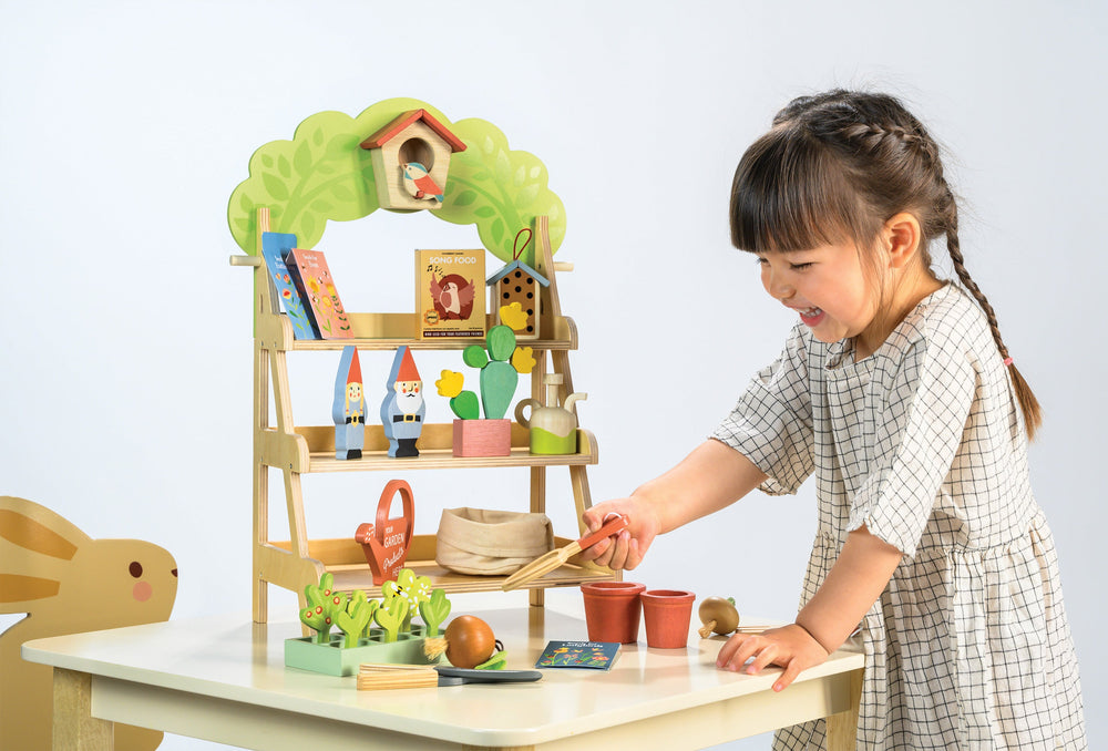 Child playing with a toy garden set on a table
