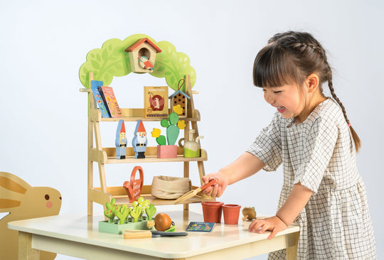 Child playing with a toy garden set on a table