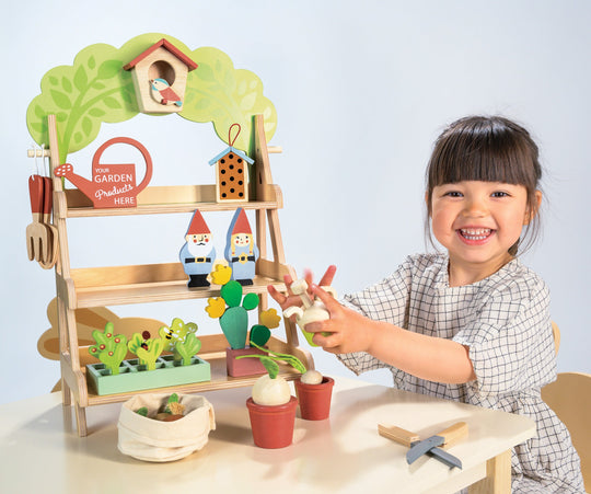 Child playing with a toy garden set on a light blue background