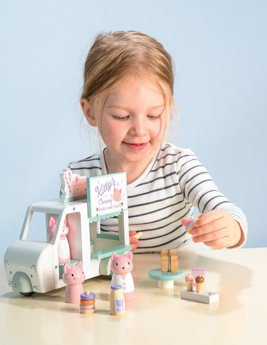 Child playing with a toy set on a table against a light blue background