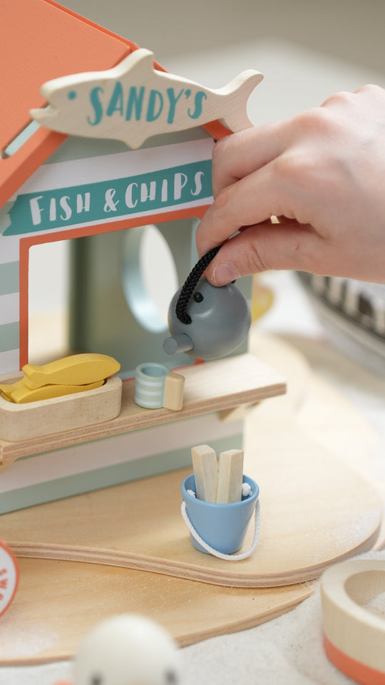 Wooden toy fish and chip shop with a hand interacting with it