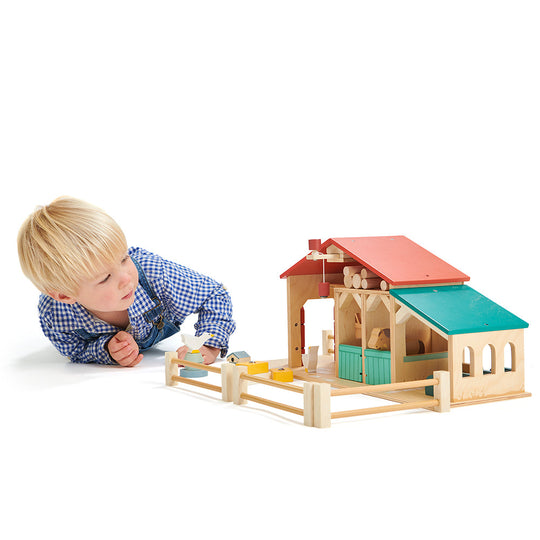 Child playing with a wooden toy house on a white background