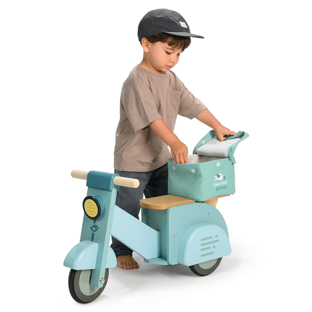 Child playing with a teal scooter on a white background