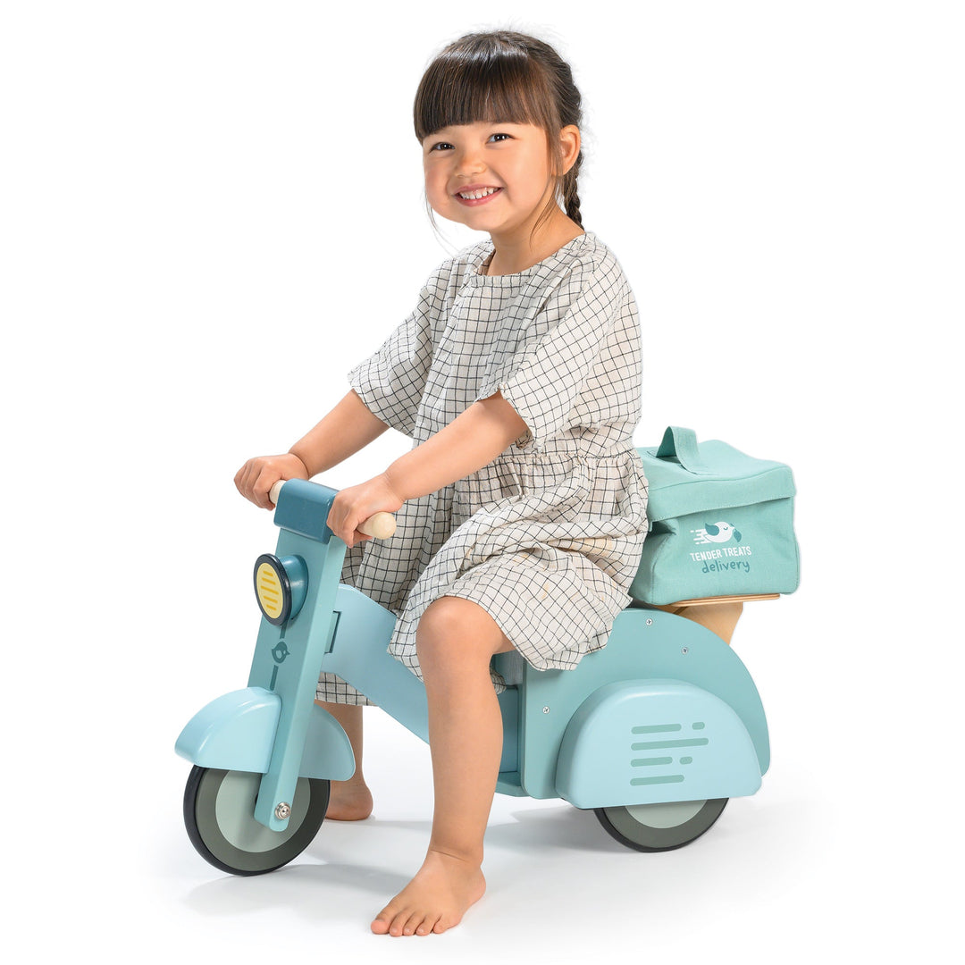 Child sitting on a light blue scooter with a white background