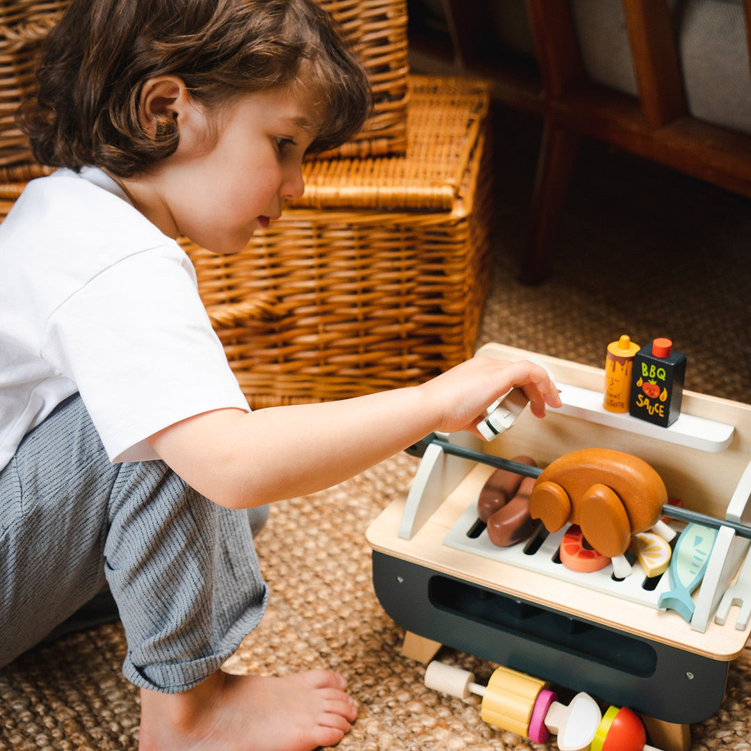 Child playing with a toy grill set on the floor