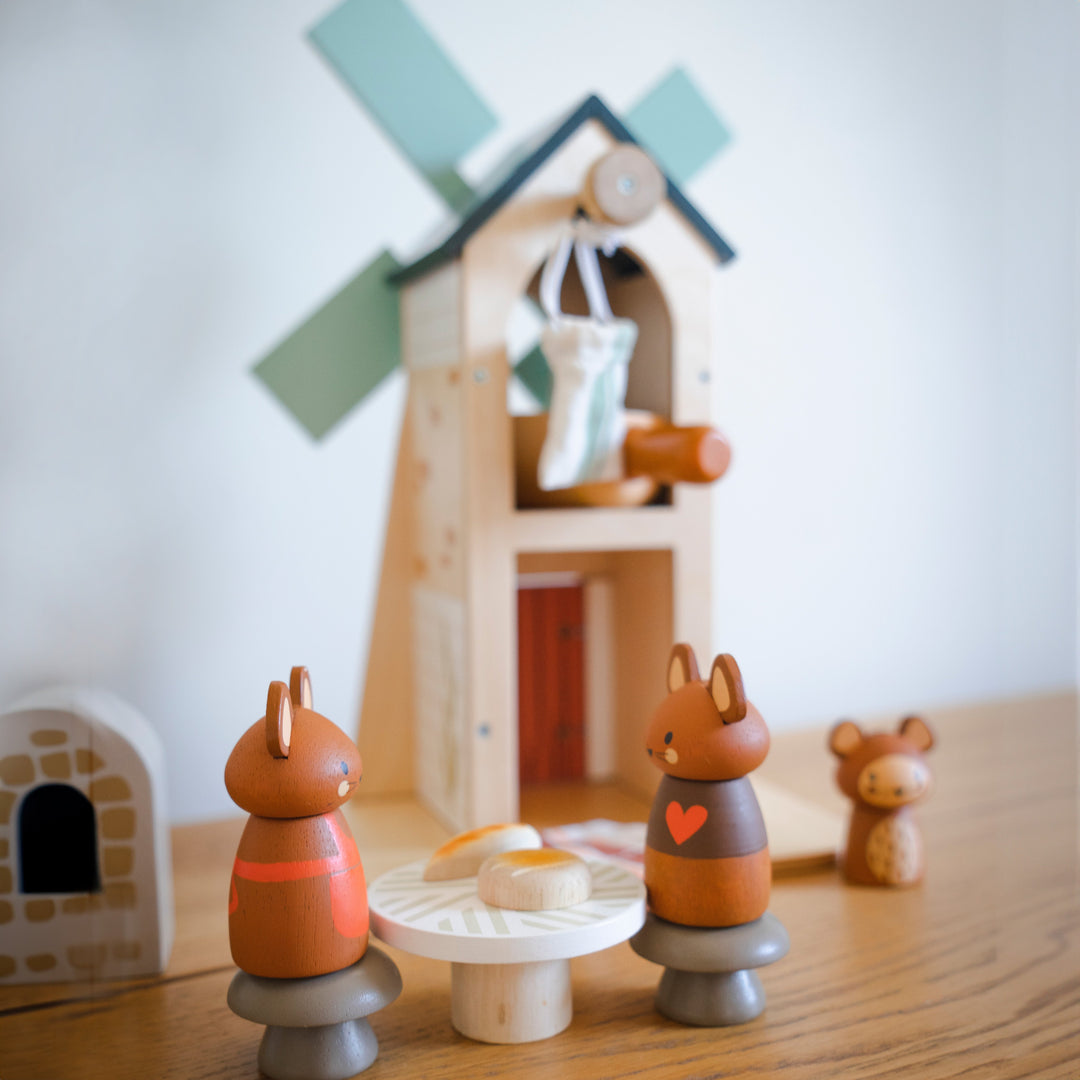 Wooden toy squirrels with a windmill and small houses in the background