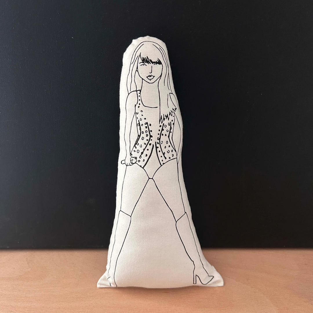 Screen printed black and white doll with Taylor Swift depicted wearing a glittery bodysuit and kneww high boots holding a microphone