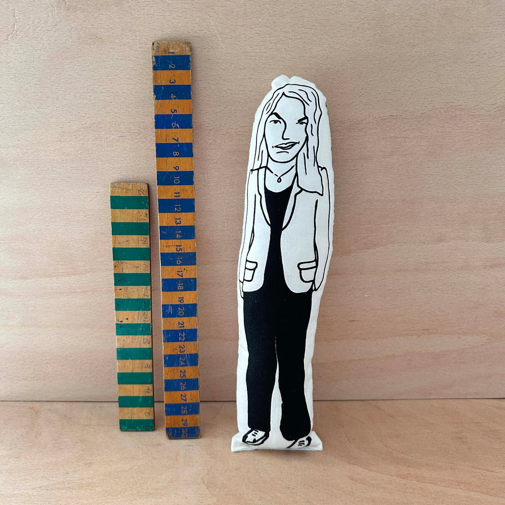 Screen printed doll of Tracey Emin wearing a suit next to two wooden rulers