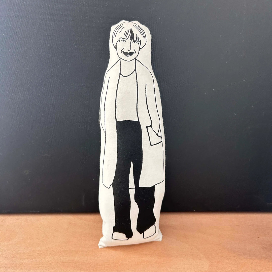Black and white screen printed doll depicting Victoria Wood on a wooden surface with a dark background