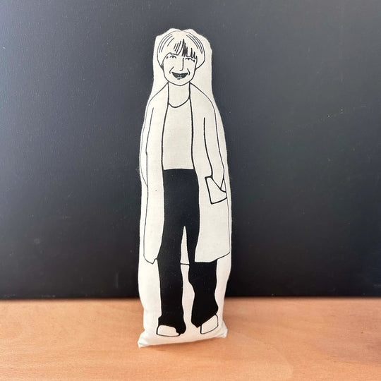 Black and white screen printed doll depicting Victoria Wood on a wooden surface with a dark background