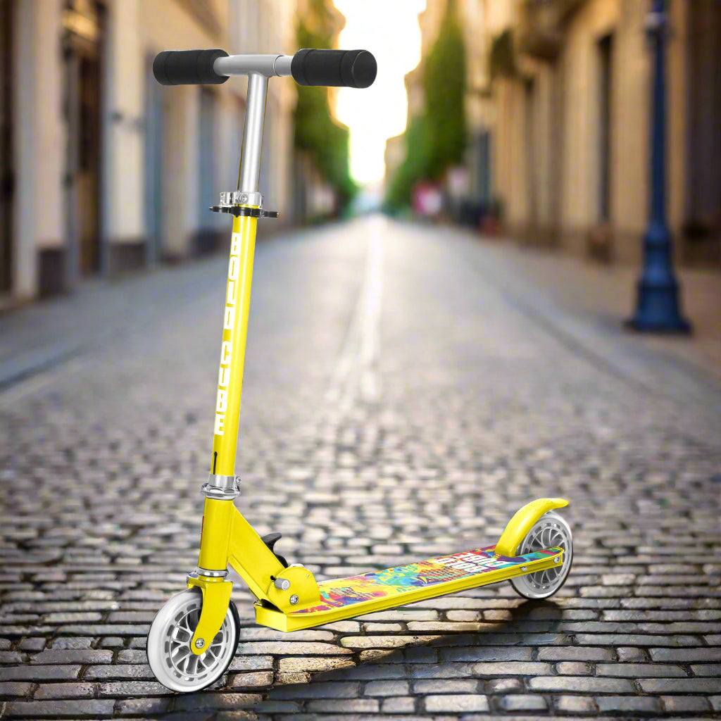 Yellow scooter with colourful deck and black handles on a cobbled pavement background
