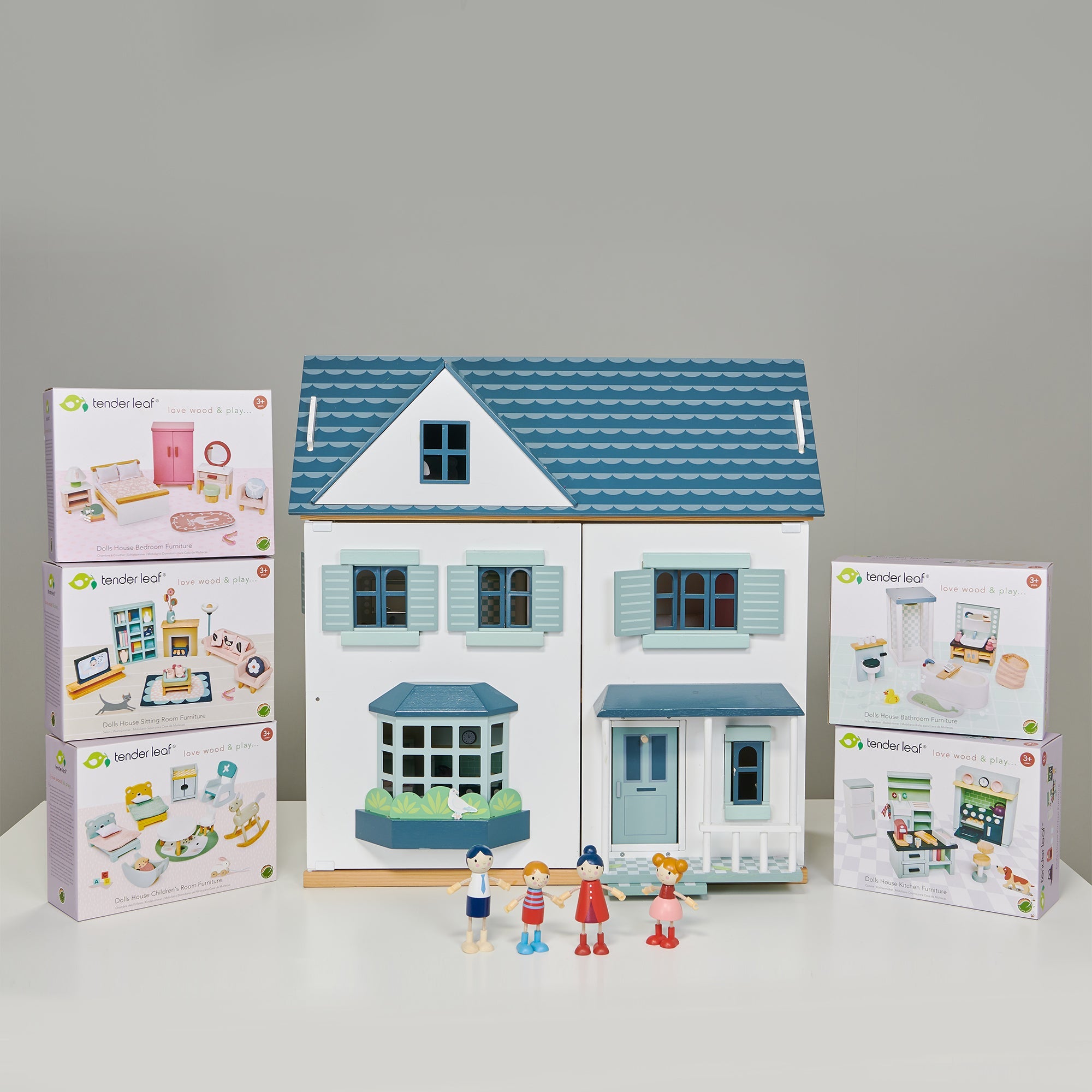Blue and white dollhouse with accessories and packaging on a grey background