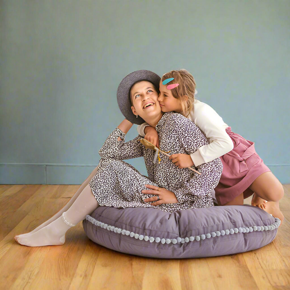 Woman and child sitting on a grey floor cushion