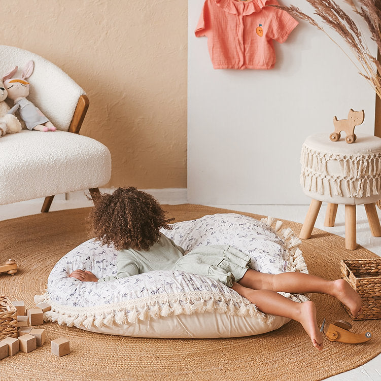 Child lying on a textured in a cosy room with toys and furniture.