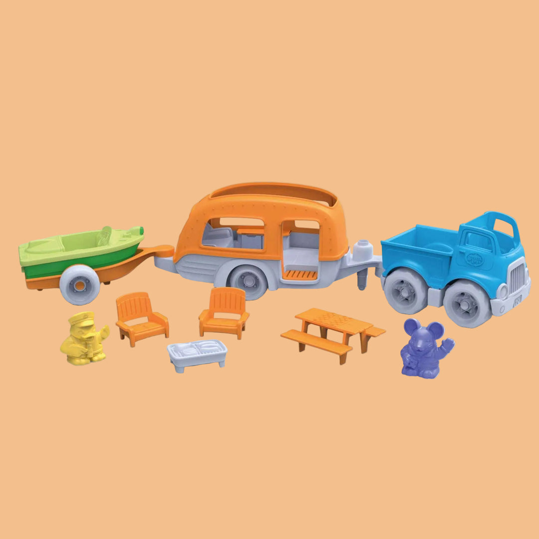 Toy set with a camper, truck, trailer, and small furniture pieces on a white background