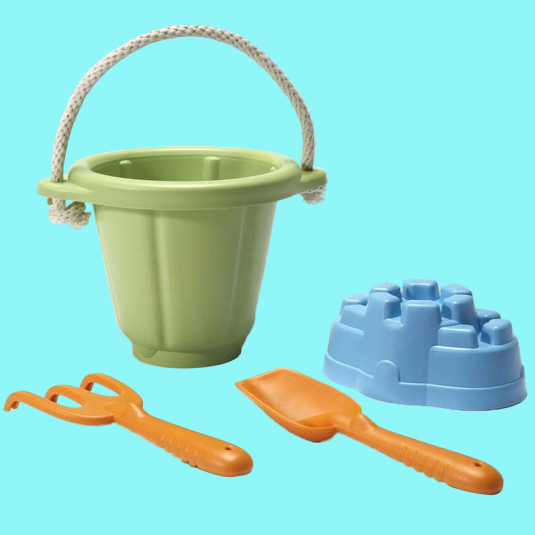 Green sand pail with rope handle, orange shovel, orange rake, and blue mold on a white background