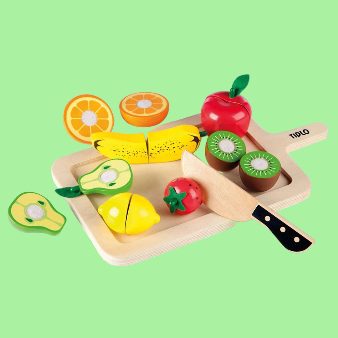 Wooden toy set with fruits and vegetables on a cutting board with a knife.