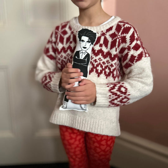 A child holding a cushion doll with a screen printed design of Robert Smith.