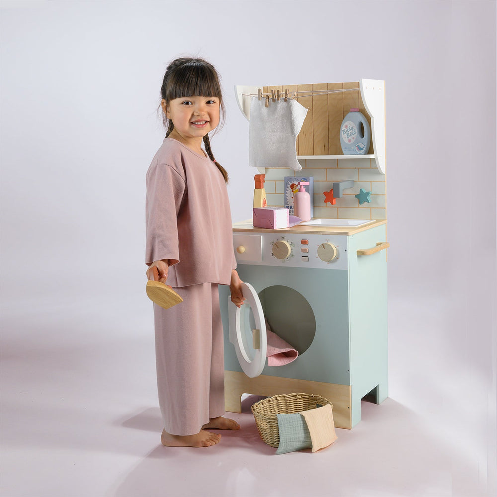 Child playing with a toy laundry set on a plain background