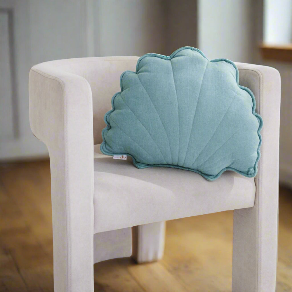 Shell-shaped blue pillow on a white chair