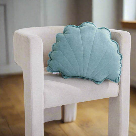 Shell-shaped blue pillow on a white chair