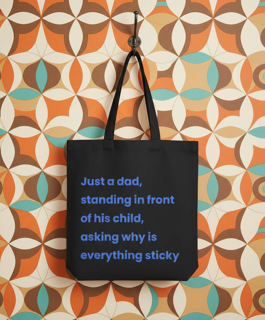 Black tote bag with blue text on a colorful geometric-patterned wall