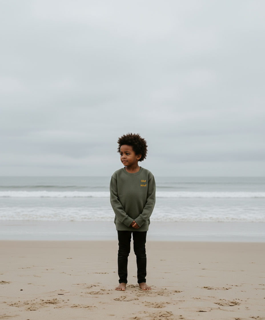 Child standing on a beach with a cloudy sky