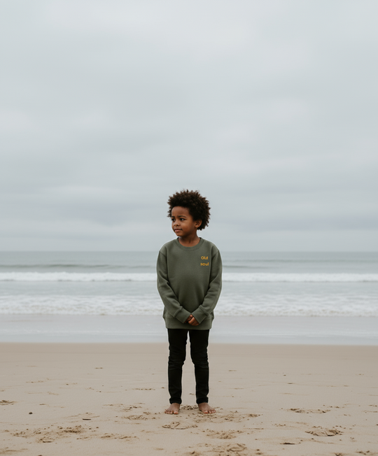 Child standing on a beach with a cloudy sky