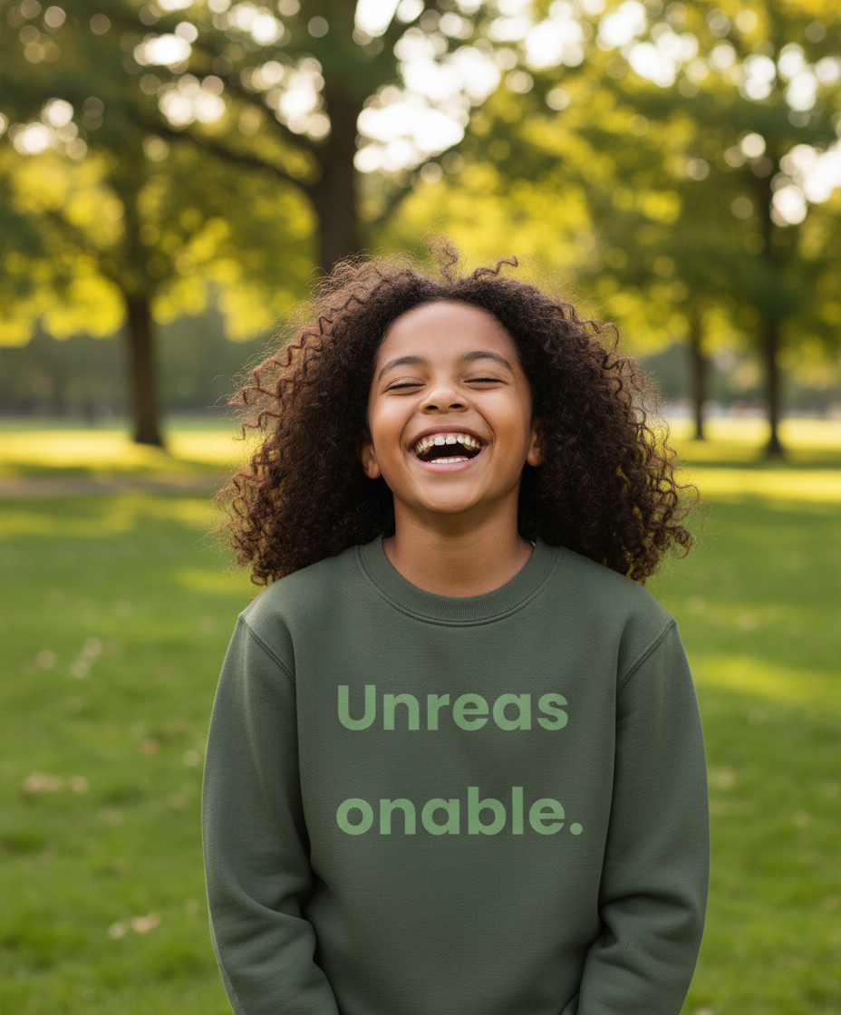Child wearing a green sweatshirt with text, standing in a park.
