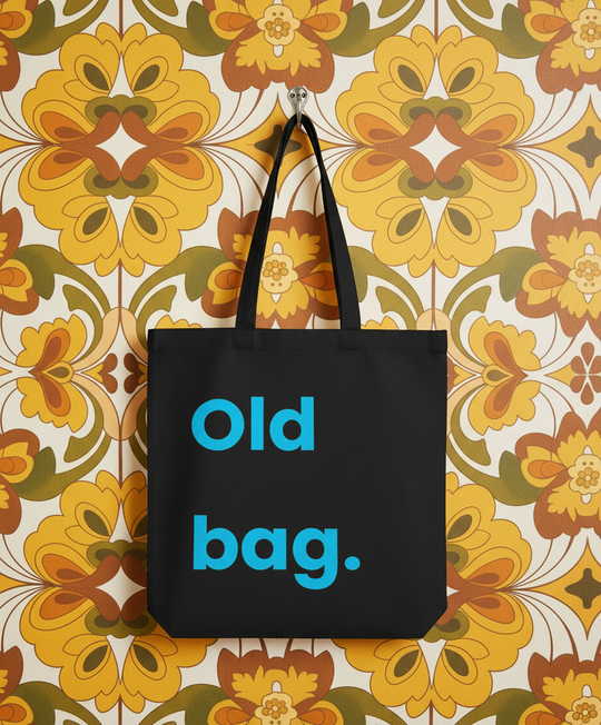 Black tote bag with 'Old bag.' text on a floral-patterned wall.