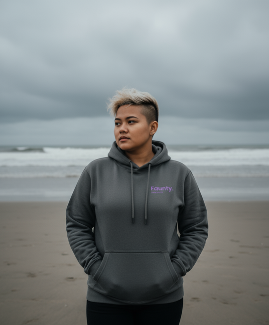 Person wearing a grey hoodie with a brand logo on a beach