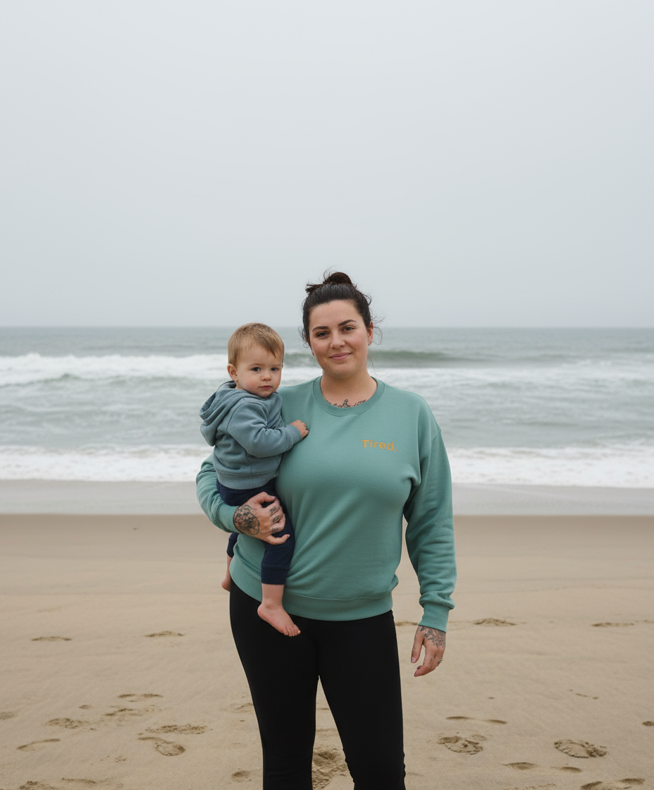 Woman holding a child on a beach with ocean waves in the background