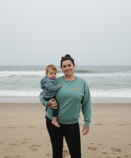 Woman holding a child on a beach with ocean waves in the background