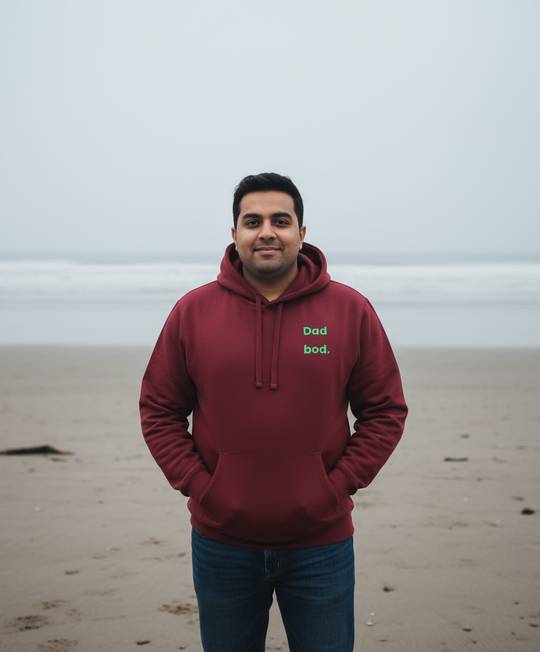 Man wearing a maroon hoodie with text on a beach