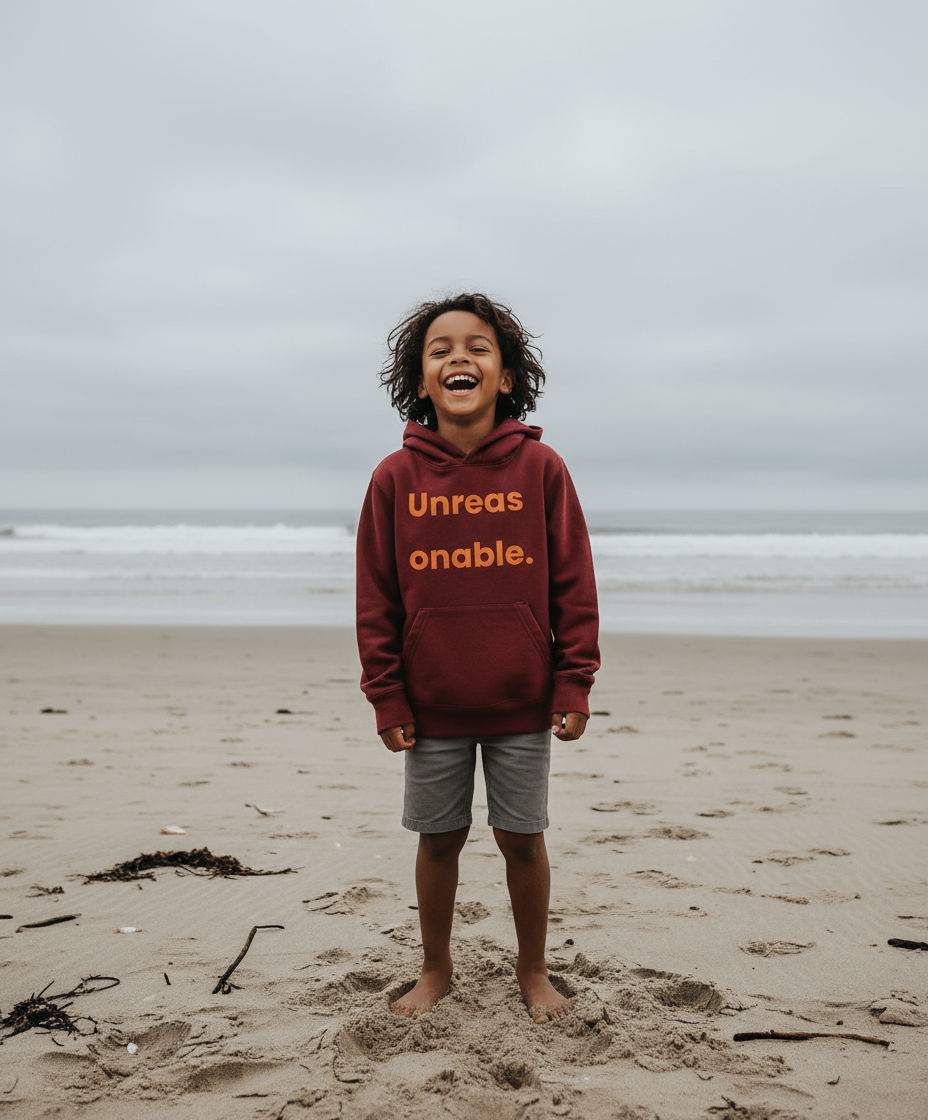 Child wearing a hoodie with text on a beach