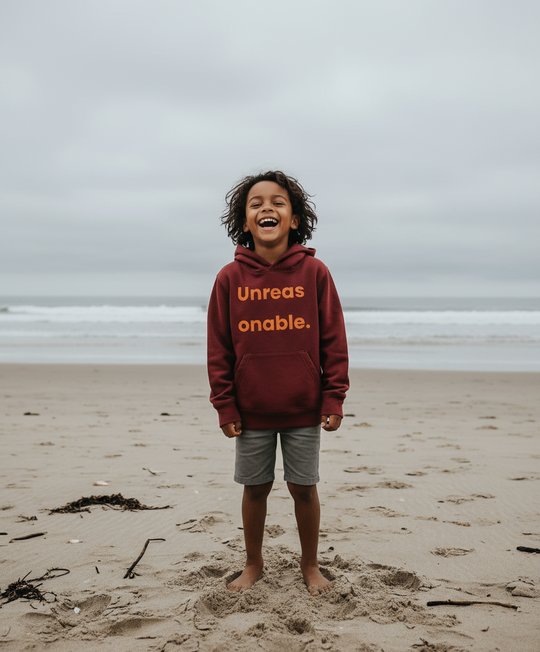 Child wearing a hoodie with text on a beach