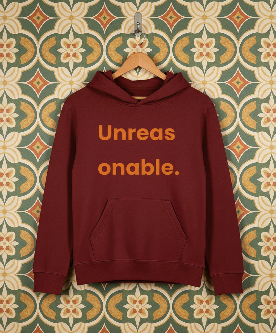 Maroon hoodie with 'Unreas onable.' text on a patterned wall background