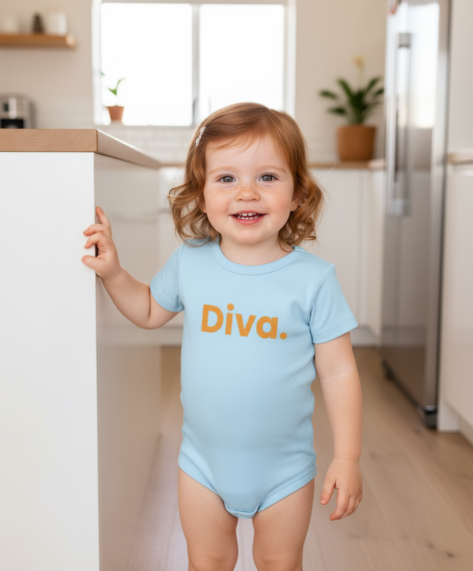Child wearing a light blue onesie with 'Diva' printed on it in a kitchen.