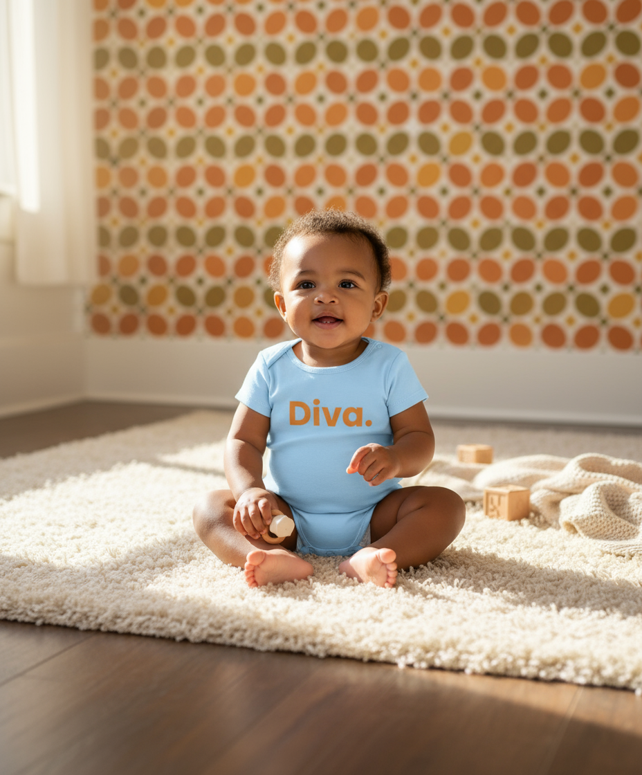 Baby sitting on a rug wearing a blue 'Diva' onesie in a room with patterned wallpaper.